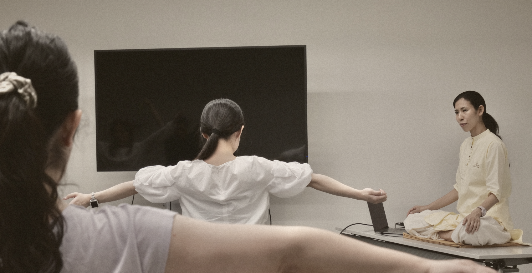 就業時間内のハタヨガクラスで、両腕を広げてポーズをとる社員たち